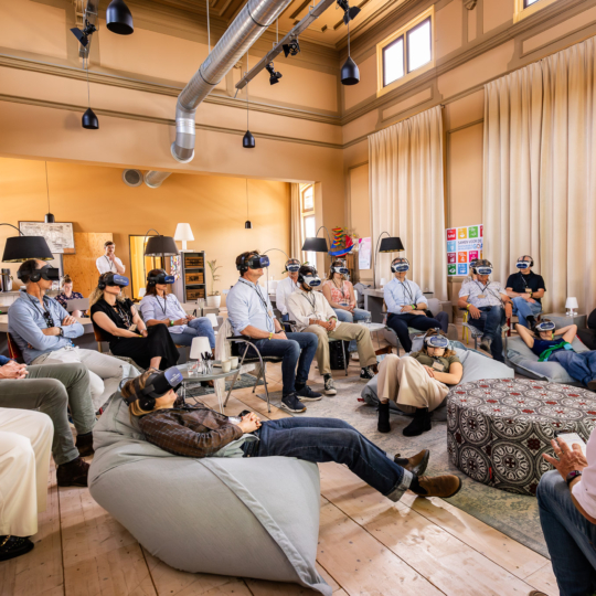 a group of people sitting in chairs with virtual reality goggles experience the overview effect