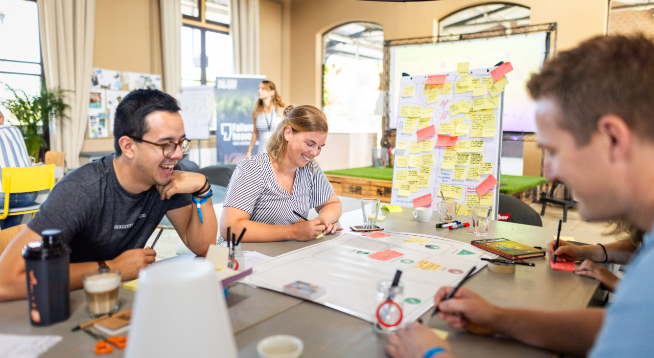 een groep mensen die aan tafel werkt aan een design thinking training